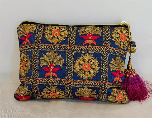 Pochette Nuit d'Or Dame en Soi — pochette zippée en tissu bleu nuit brodé de rosaces et de palmettes dorées, touches rouges et orange, pompon fuchsia