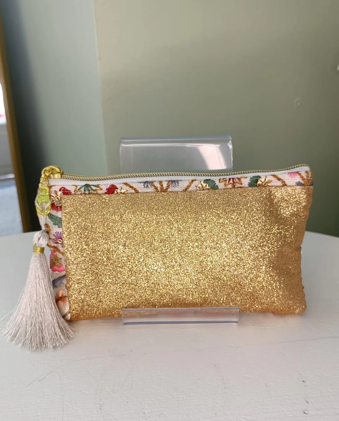 Pochette Paillette Dame en Soi — pochette zippée dorée pailletée, liseré de tissu brodé fleuri et pompon ivoire