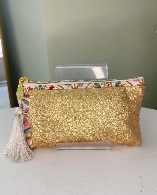 Pochette Paillette Dame en Soi — pochette zippée dorée pailletée, liseré de tissu brodé fleuri et pompon ivoire
