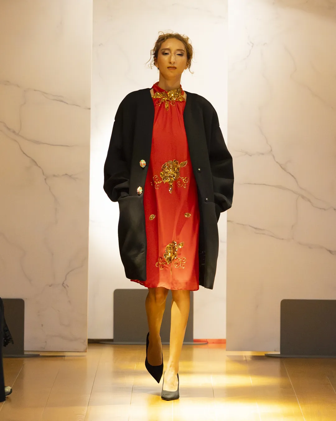 Robe Vermillon Dame en Soi — robe droite rouge brodée de motifs dorés portée sous un manteau noir oversize, défilé Galeries Lafayette