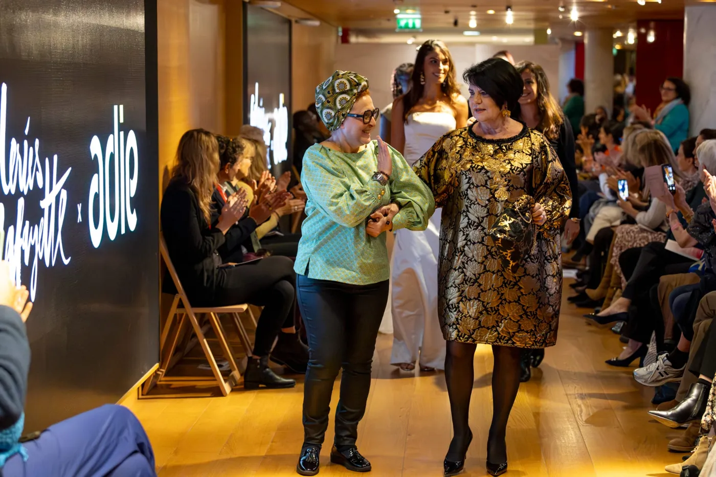 Final du défilé Dame en Soi aux Galeries Lafayette avec l'Adie — la créatrice salue le public aux côtés d'un modèle